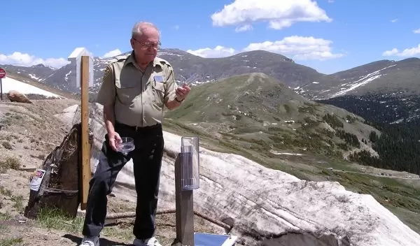 citizen scientist with rain gauge in Rocky Mountains