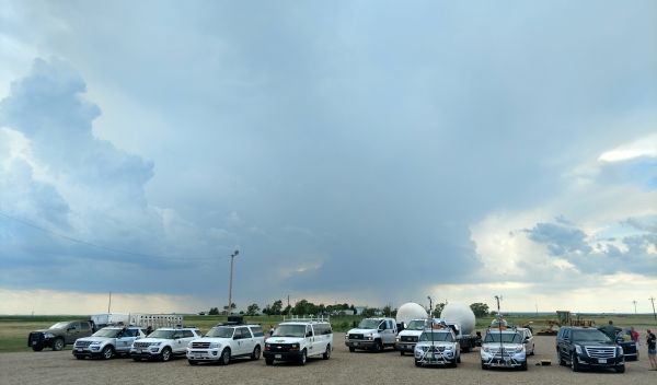 multiple vehicles in an open field under a daunting sky