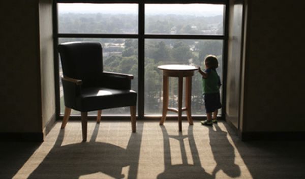 Child looking outside the window from a high floor