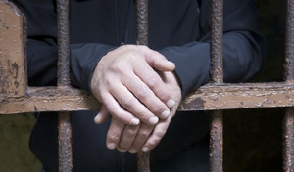 hands of a man behind bars