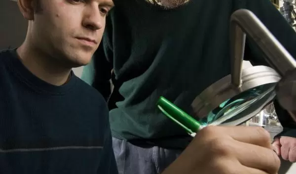 Photo of Richard Lenski and another researcher examining a Petri dish used in a study of evolution.