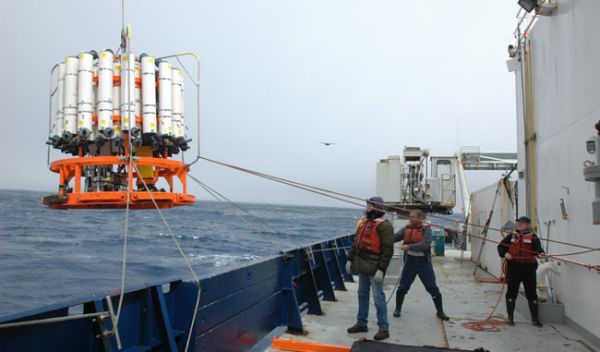 Photo of 3 crew members, "tag lines" and equipment on the ship's deck.