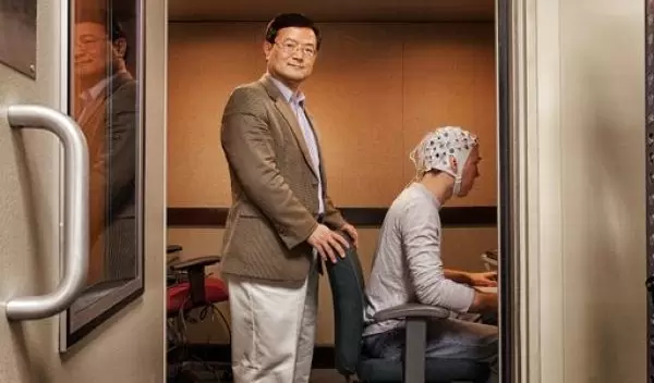 Bin He standing next to a subject wearing a hat with electorodes