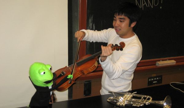 Photo of Ryan Miyakawa warming up the orchestra before recording The Nano Song.