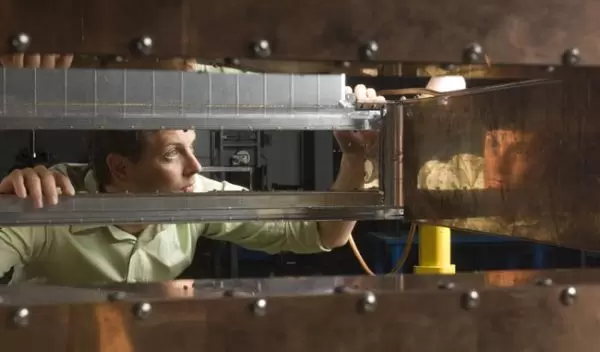 Photo of Matt Johnson, NSCL staff engineer, inspecting a 45-degree dipole magnet