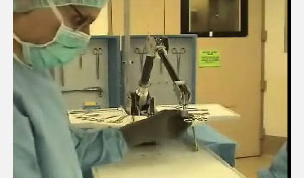 Screen capture from video showing surgeon and robot in an operating room