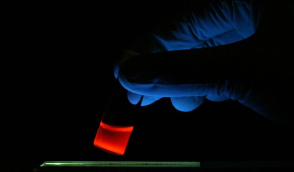 Photo of luminescent porous silicon nanoparticles in a vial illuminated with ultraviolet light.