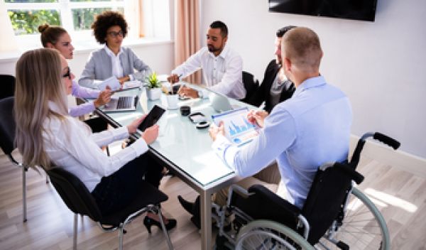 Group including women, minorities, and persons with disabilities work at a table.