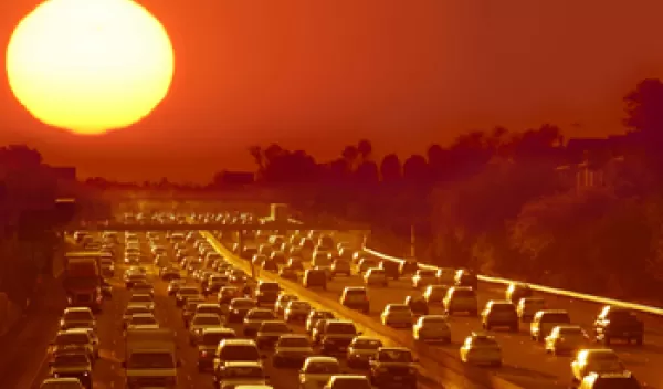 Photo of sun radiating over highway filled with cars in traffic in Phoenix