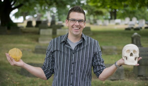 Timothy Verstynen in graveyard holding a plastic skull and brain.