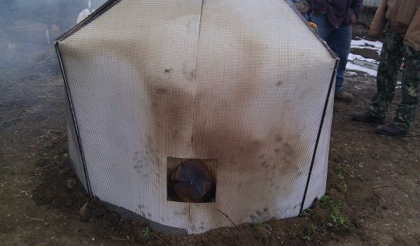 A tent-like kiln over woody waste material