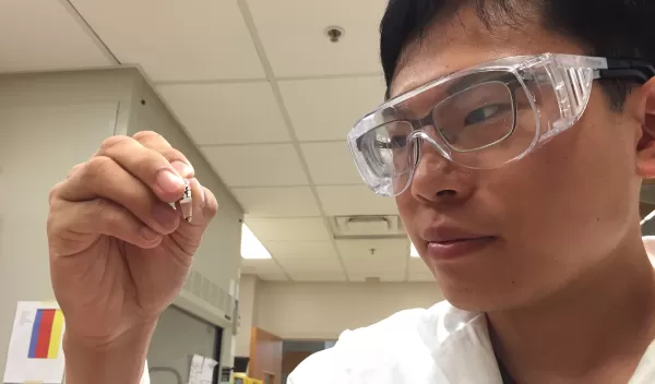 Student holding a sample for rsearch in the lab