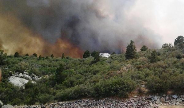 Photo of wildfire next to a house and forest in Arizona