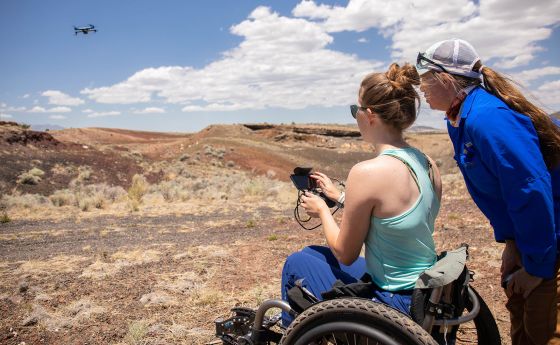 woman sitting in wheel chair controlling a flying drone