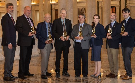 a group of 8 people that received awards wearing suits