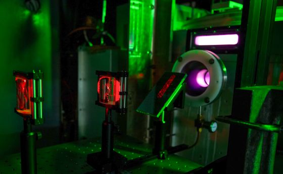 A laser table in a dark lab with red laser light visible and optical equipment.