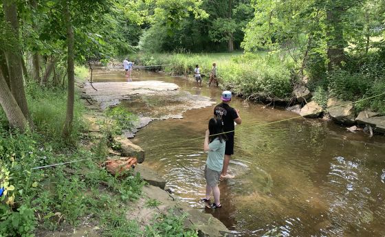 people standing in a body of shallow water fishing