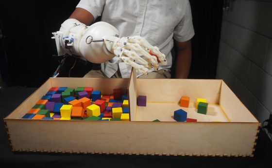 Wearable anthropomorphically driven prosthesis with built in haptic feedback system playing with colorful blocks