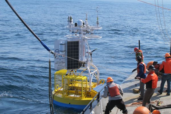 Workers on a ship releasing a scientific buoy into the ocean