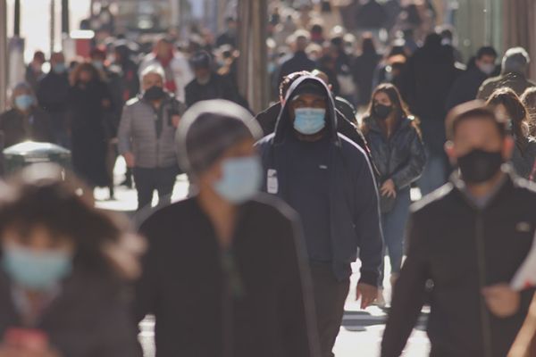 People walking on a city sidewalk wearing masks during the coronavirus epidemic.