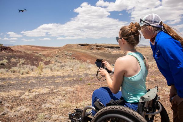 woman sitting in wheel chair controlling a flying drone