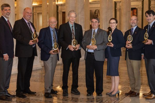 a group of 8 people that received awards wearing suits