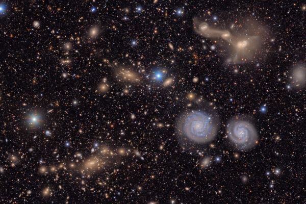 Many stars and galaxies including two spiral galaxies and three merging galaxies.