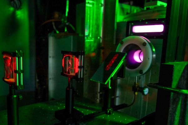 A laser table in a dark lab with red laser light visible and optical equipment.