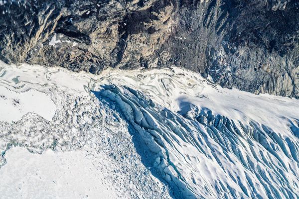 An aerial view of where bedrock, sea ice, a glacial river, crevasses, and icebergs meet. Western Greenland Ice Sheet.