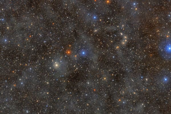 A dense field of colorful stars shining through a dust cloud